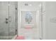 Elegant bathroom featuring glass enclosed shower, modern tub under arched window, and white cabinetry at 4610 W Browning Ave, Tampa, FL 33629
