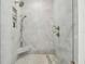 Close-up of glass-enclosed shower with marble walls, modern fixtures, and a built-in shelf at 4610 W Browning Ave, Tampa, FL 33629