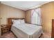 Cozy bedroom with a comfortable bed, side table, and a window with light filtering through its decorative curtains at 5538 Antigua Dr, Zephyrhills, FL 33541