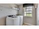 Bright laundry room features modern washer and dryer with shelving and a view from the window at 5636 Silver Moonlight Dr, Palmetto, FL 34221