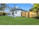 Exterior view of the home's backyard featuring a well-maintained lawn, wood fence, and stone paver walkway at 6326 22Nd N Ave, St Petersburg, FL 33710