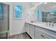 Bathroom featuring double vanity, framed mirrors, and a glass-enclosed shower at 724 Winterside Dr, Apollo Beach, FL 33572