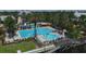 An aerial showcases the community pool with a slide, a lighthouse feature, landscaping and lounge chairs next to a picturesque lake at 724 Winterside Dr, Apollo Beach, FL 33572