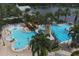 Aerial view of a community pool with a slide, splash area, a lighthouse feature, and palm trees next to a beautiful lake at 724 Winterside Dr, Apollo Beach, FL 33572
