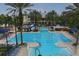Community pool featuring lap lanes, a slide, and blue-and-white striped umbrellas, surrounded by palm trees at 724 Winterside Dr, Apollo Beach, FL 33572