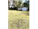 Expansive backyard features two storage sheds and a spacious lawn, surrounded by trees at 7608 Chenkin, Zephyrhills, FL 33540