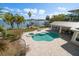 Aerial view showcases a sparkling pool and jacuzzi, covered patio, and boat dock with lift at 901 Bay Esplanade, Clearwater Beach, FL 33767