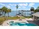 Home's backyard features a sparkling pool and jacuzzi, dock, and boat lift on a sunny day at 901 Bay Esplanade, Clearwater Beach, FL 33767