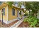 Exterior view of home showing charming yellow siding, landscaping and sidewalk to entry at 1045 6Th N St, St Petersburg, FL 33701