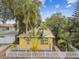 Charming house with a metal roof surrounded by palm trees and lush vegetation, enclosed by a white picket fence at 1045 6Th N St, St Petersburg, FL 33701