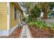 Landscaped side yard with a concrete walkway, lush greenery, and a white picket fence, enhancing the property's appeal at 1045 6Th N St, St Petersburg, FL 33701