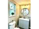 Cozy bathroom featuring a modern vanity, round mirror, updated lighting, and a view to the outdoors at 1101 Canal St, Ruskin, FL 33570