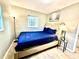 Cozy bedroom with a tufted headboard, blue bedding, and ample natural light from the window, on hardwood floors at 1101 Canal St, Ruskin, FL 33570