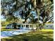 Rear view of home with sunroom, mature trees, and large driveway at 1101 Canal St, Ruskin, FL 33570