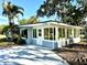 Rear view of home with sunroom, mature trees, and large driveway at 1101 Canal St, Ruskin, FL 33570