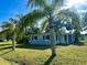 Quaint single-story home with a light blue exterior, dark shutters, and a well-manicured lawn with palm trees at 1101 Canal St, Ruskin, FL 33570