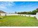 Large backyard with a white fence, green grass, a grill, and beautiful plantings at 12018 Gillingham Harbor Ln, Gibsonton, FL 33534