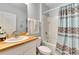 Bathroom showcasing wood counter, a sink, a toilet, and a shower behind a patterned curtain at 12018 Gillingham Harbor Ln, Gibsonton, FL 33534