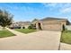 A tan single Gathering home is displayed with a manicured lawn and an attached two car garage at 12018 Gillingham Harbor Ln, Gibsonton, FL 33534