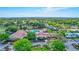 Aerial view of clubhouse with pool, tennis courts, and manicured landscaping, surrounded by lush greenery at 1487 Dundee Dr, Palm Harbor, FL 34684