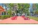 Outdoor picnic area with red tables and benches, surrounded by trees and landscaping near the lake at 1487 Dundee Dr, Palm Harbor, FL 34684