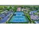 Aerial view of multiple well-maintained tennis courts alongside a parking lot and clubhouse at 1487 Dundee Dr, Palm Harbor, FL 34684