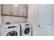 Efficient laundry room featuring a modern washer and dryer, and convenient overhead cabinet storage at 18005 Tavernside Trl, Lakewood Ranch, FL 34211