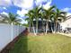 Landscaped backyard with a screened pool, lush lawn, tropical palms, and a white fence for added privacy at 3600 105Th N Ave, Clearwater, FL 33762