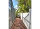 Side yard walkway features pavers, rock landscaping, and tropical foliage with a white fence at 3600 105Th N Ave, Clearwater, FL 33762