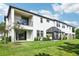 Townhome backyard featuring covered patio, balcony, lush lawn, and partial privacy fence at 5095 San Martino Dr, Wesley Chapel, FL 33543