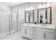 Modern bathroom with double vanity, large mirrors, and a sleek glass-enclosed shower at 5095 San Martino Dr, Wesley Chapel, FL 33543