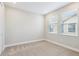 Bright bedroom featuring neutral carpet, two windows with blinds, and fresh paint at 5095 San Martino Dr, Wesley Chapel, FL 33543