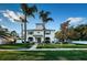 Charming two-story home featuring blue shutters, a manicured lawn, and mature palm trees under a clear blue sky at 614 Maryland Ave, Crystal Beach, FL 34681