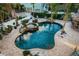 Aerial view of a private pool and spa, enhanced by decorative rock features and lush greenery at 614 Maryland Ave, Crystal Beach, FL 34681