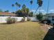 Backyard with grass, palm trees, bird bath, and white vinyl fence at 66 Kipling Plz, Clearwater Beach, FL 33767