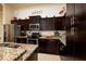 A kitchen features dark wood cabinetry with granite countertops and stainless steel appliances at 707 Highland N St, St Petersburg, FL 33701