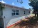 Side exterior view of the home showing recent paint and mulch bed at 7908 Rideout Rd, Tampa, FL 33619