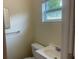 Cozy powder room featuring a white sink, toilet, and mirror next to a window for natural light at 8969 109Th Ter, Seminole, FL 33777