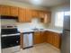 Well-lit kitchen with modern stainless steel appliances, tiled floor and wood cabinetry at 8969 109Th Ter, Seminole, FL 33777