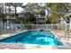 Inviting community pool with lounge chairs, surrounded by a fence and lush trees at 9920 Indian Key Trl # 29, Seminole, FL 33776