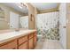 Well-lit bathroom featuring a vanity with sink and tiled shower/tub combo, with a floral curtain at 12402 Country White Cir, Tampa, FL 33635