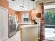 Well-lit kitchen featuring stainless steel appliances, wood cabinets, and access to the outdoor living space at 12402 Country White Cir, Tampa, FL 33635