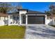 Charming one-story home featuring a gray brick driveway, manicured lawn, and a two-car garage at 1409 W Wood St, Tampa, FL 33604