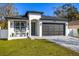 A beautifully designed white home with a striking black garage door and a neatly maintained green lawn at 1409 W Wood St, Tampa, FL 33604