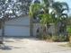 Home exterior featuring attached garage and tropical landscaping at 1440 Hales Hollow Dr, Dunedin, FL 34698