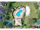 Aerial view of a swimming pool with lounge chairs, clubhouse, tennis court and residential homes surrounded by verdant landscaping at 1604 Mira Lago Cir, Ruskin, FL 33570