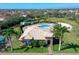 Aerial view of a community clubhouse with a pool, lounge area, tennis court, and lush green landscaping at 1604 Mira Lago Cir, Ruskin, FL 33570