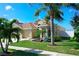 Beautifully landscaped single Gathering home features a three-car garage, mature palms, and lush green lawn at 1604 Mira Lago Cir, Ruskin, FL 33570