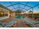 A screened-in pool area with lounge chairs, a waterfall feature, and lush landscaping at 2011 Captiva Ct, Sun City Center, FL 33573