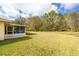 Expansive backyard with lush green grass, with a screened-in patio and mature trees at 29447 Schinnecock Hills Ln, San Antonio, FL 33576